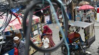 Warga berjalan di bawah instalasi jaringan kabel utilitas yang semrawut di Medan, Sumatera Utara, Sabtu (5/8/2023). 