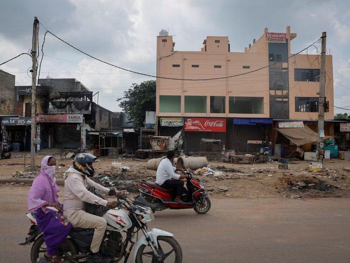 People ride past the burnt shops following clashes between Hindus and Muslims in Gurugram district in the northern state of Haryana, India, August 1, 2023. REUTERS/Adnan Abidi