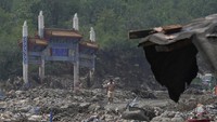 Seorang pria berjalan di dekat gerbang usai banjir yang menghancurkan desa Nanxinfang di pinggiran Beijing, Jumat, 4 Agustus 2023.