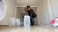 Seorang pekerja mendorong balok es di tengah permintaan es yang belum pernah terjadi sebelumnya karena cuaca semakin panas dan suhu mencapai rekor tertinggi di Sanaa, Yaman. 