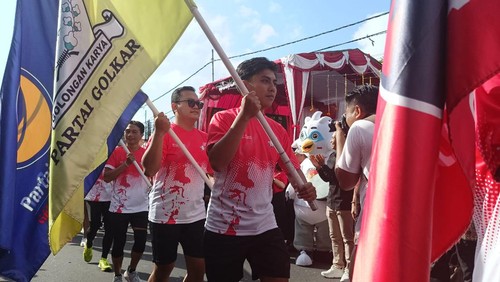 Puluhan pelari sembari membawa bendera partai politik berlari mengelilingi Lapangan Bajra Sandhi, Renon, Denpasar, Bali pada Minggu (6/8/2023).