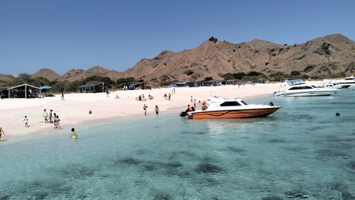 Pemandangan indah pantai Long Pink Beach: pasir berwarna merah muda, laut biru, dan gugusan bukit. (Ambrosius Ardin)