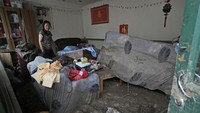 Salah seorang warga nampak kebingungan menemukan barang-barangnya berlapis lumpur usai banjir menerjang. 