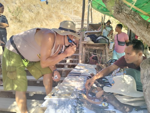 Seorang wisatawan mancanegara berbelanja suvenir di Pulau Padar seusai menyelesaikan treking. (Ambrosius Ardin)