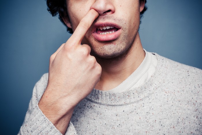 Young multi racial man is picking his nose