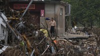 Seorang penduduk mengumpulkan barang-barangnya dari desa yang dilanda banjir di pinggiran Beijing. Dalam foto yang diambil pada Jumat, 4 Agustus 2023, sejumlah rumah warga rusak parah usai diterjang topan Doksuri.  
