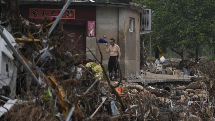 A resident collects his belongings from a flood ravaged village on the outskirts of Beijing, Friday, Aug. 4, 2023. Heavy rain and high water levels on rivers in northeastern China were threatening cities downstream on Friday, prompting the evacuation of thousands, although the country appears to have averted the worst effects of the typhoon season battering parts of east Asia. (AP Photo/Ng Han Guan)