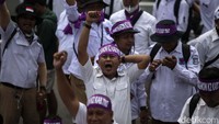 Massa mengenakan baju kaos warna putih dan pita warna merah serta ikat kepala bertuliskan honorer.  