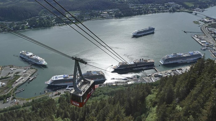 People mill about on the sea walk along which cruise ships dock on June 12, 2023, in downtown Juneau, Alaska. Buses stand ready to take tourists to activities around town. As the Mendenhall Glacier continues to recede, tourists are flooding into Juneau. A record number of cruise ship passengers are expected this year in the city of about 30,000 people.(AP Photo/Becky Bohrer)