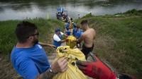 Para relawan bahu membahu mengumpulkan sampah yang mengalir ke hilir.  