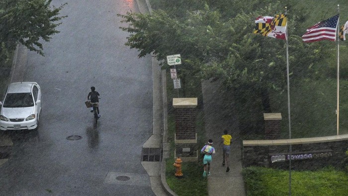 People sprint for shelter as a line of thunderstorms hit downtown Towson, Md., Monday, Aug. 7, 2023. (Jerry Jackson/The Baltimore Sun via AP)