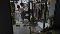 Warga membersihkan butik dari lumpur sisa banjir.  