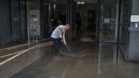 Pekerja membersihkan air lumpur dari pintu masuk apartemen.  