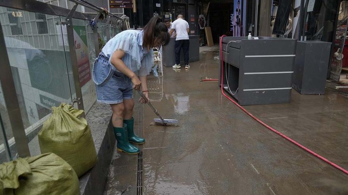 Banjir di China Surut, Warga Bersih-bersih Toko Workers clear mud water from an apartment entrance gate in the aftermath of flood waters from an overflowing river in the Mentougou district on the outskirts of Beijing, Monday, Aug. 7, 2023. Rain continued to pelt northeastern China in the wake of Typhoon Doksuri, as authorities reported more fatalities and missing people while evacuating thousands more. (AP Photo/Andy Wong)