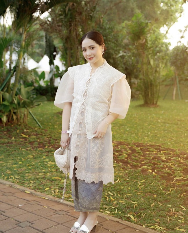Kemudian hadir Nagita Slavina yang tampak anggun mengenakan kebaya modern warna putih. Model kebaya Nagita Slavina yang unik dengan potongan lengan puff menambah kesan elegan dan menarik atensi. Foto: Instagram @raffinagita1717