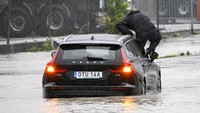 Seorang pria keluar dari mobil yang terjebak di bundaran banjir di Arlov, di sepanjang jalan E6 di luar Malmo, Swedia selatan, Senin, 7 Agustus 2023. Cuaca badai di wilayah Laut Baltik menyebabkan penundaan bandara, menghentikan layanan feri , pemadaman listrik kecil dan banyak hujan. 