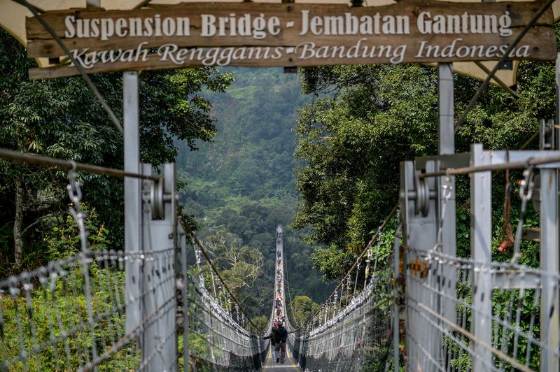 Pengunjung menyeberangi jembatan gantung rengganis di Patengan, Rancabali, Kabupaten Bandung, Jawa Barat, Selasa (8/8/2023). Jembatan Gantung Rengganis yang memiliki panjang mencapai 370 meter, lebar dua meter serta berada di ketinggian 150 meter dari tanah tersebut merupakan jembatan gantung terpanjang di Asia Tenggara. ANTARA FOTO/Raisan Al Farisi/hp.