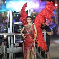 Yuki Kato tampil merah membara di sesi karnaval malam hari. Aktris 28 tahun ini mengenakan gaun bergradasi dengan material kain lipit transparan. Foto: Instagram/@cassava.photography