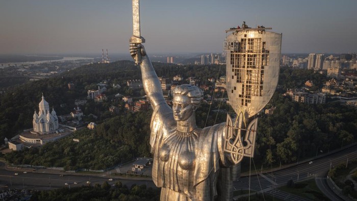Workers install the Ukrainian coat of arms on the shield in the hand of the country's tallest stature, the Motherland Monument, after the Soviet coat of arms was removed, in Kyiv, Ukraine, Sunday, Aug. 6, 2023. Ukraine is accelerating efforts to erase the vestiges of centuries of Soviet and Russian influence from the public space amid the Russian invasion of Ukraine by pulling down monuments and renaming hundreds of streets to honor home-grown artists, poets, military chiefs, and independence leaders. (AP Photo/Efrem Lukatsky)