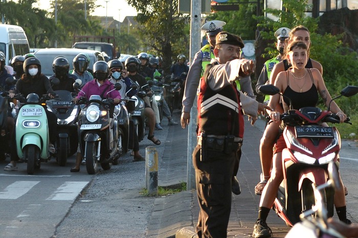 Petugas membagikan helm kepada wisatawan mancanegara yang tidak mengenakan helm saat sosialisasi tertib berlalu lintas di kawasan Seminyak, Badung, Bali, Selasa (8/8/2023). Kegiatan yang diselenggarakan Korlantas Polri bersama PT Jasa Raharja itu sebagai kampanye untuk meningkatkan keselamatan berkendara dan menurunkan angka kecelakaan di kawasan wisata Pulau Dewata khususnya bagi wisatawan mancanegara. ANTARA FOTO/Fikri Yusuf/Spt.