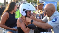 Petugas membagikan helm kepada wisatawan mancanegara yang tidak mengenakan helm saat sosialisasi tertib berlalu lintas di kawasan Seminyak, Badung, Bali, Selasa (8/8/2023). 