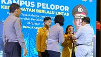 Direktur Hubungan Kelembagaan PT Jasa Raharja Munadi Herlambang menyerahkan pin keselamatan kepada mahasiswa dan mahasiswi di Universitas Pendidikan Nasional Denpasar, Bali. 