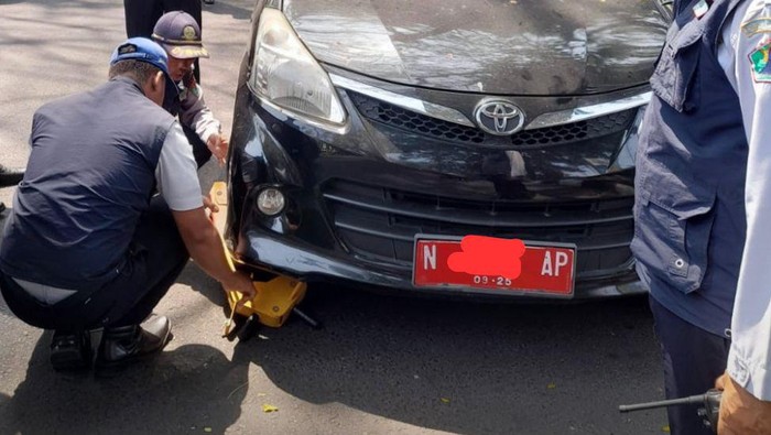 Petugas Dishub Kota Malang menggembok mobil ASN berpelat merah.