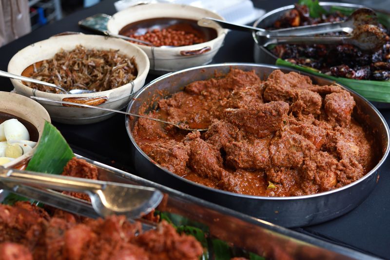 Various choice of Nasi Lemak dishes, chicken rendang, ayam goreng berempah, anchovies, roasted peanuts, hard boiled egg and spicy sambal at market stall.