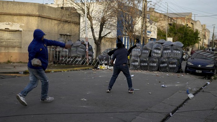 Demonstrators throw pieces of concrete at a cordon of riot police during a protest against the death of 11-year-old Morena Dominguez, who died from her injuries after criminals tried to rob her, outside a police station on the outskirts of Buenos Aires, Argentina, Wednesday, Aug. 9, 2023. (AP Photo/Natacha Pisarenko)
