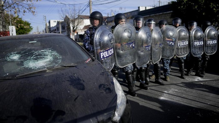 Demonstrators throw pieces of concrete at a cordon of riot police during a protest against the death of 11-year-old Morena Dominguez, who died from her injuries after criminals tried to rob her, outside a police station on the outskirts of Buenos Aires, Argentina, Wednesday, Aug. 9, 2023. (AP Photo/Natacha Pisarenko)