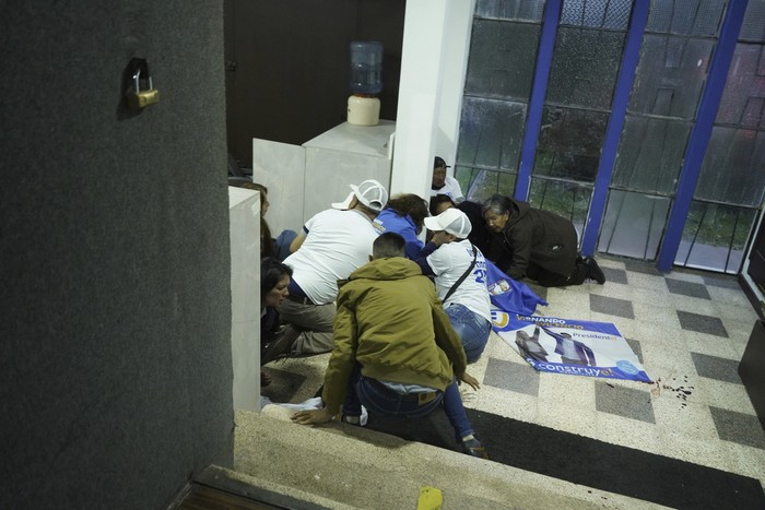 Supporters of presidential candidate Fernando Villavicencio take cover after he was shot and killed at the end of a campaign rally outside a school in Quito, Ecuador, Wednesday, Aug. 9, 2023. (API via AP)
