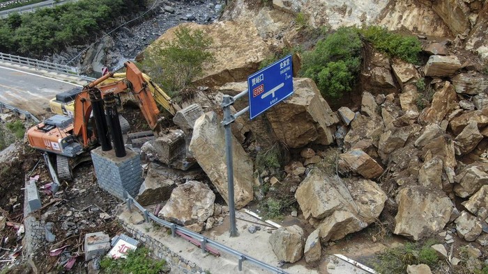 Potret Kerusakan Akibat Banjir di Beijing, Jumlah Korban Tewas Bertambah In this photo released by Xinhua News Agency, heavy machinery remove rocks fallen on a road in the aftermath of rainstorms in Shijiaying Town of Fangshan District on the outskirts of Beijing on Sunday, Aug. 6, 2023. Multiple people including rescuers have been killed in recent flooding in China's capital, and many others are missing, officials said Wednesday, as much of the country's north remains threatened by unusually heavy rainfall. (Ju Huanzong/Xinhua via AP)