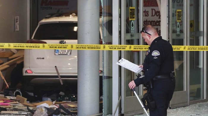 Potret Mobil Seruduk Dealer Toyota di Los Angeles Police investigators survey the scene of a vehicle crash at the service center for a Toyota Auto Dealership in the Mission Hills neighborhood of Los Angeles on Wednesday, Aug. 9, 2023. The vehicle driven by a customer entered the service area of dealership and struck a few people Wednesday, killing one of the injured who was briefly trapped beneath the vehicle, authorities and witnesses say. (AP Photo/Richard Vogel)