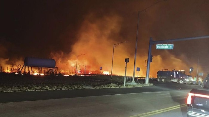Pulau Hawaii Hancur Gegara Kebakaran Hutan, 6 Orang Tewas This photo provided by County of Maui shows fire and smoke filling the sky from wildfires on the intersection at Hokiokio Place and Lahaina Bypass in Maui, Hawaii on Tuesday, Aug. 8, 2023. Wildfires in Hawaii fanned by strong winds burned multiple structures in areas including historic Lahaina town, forcing evacuations and closing schools in several communities Wednesday, and rescuers pulled a dozen people escaping smoke and flames from the ocean. (Zeke Kalua/County of Maui via AP)