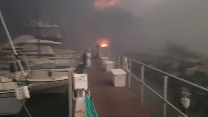 Pulau Hawaii Hancur Gegara Kebakaran Hutan, 6 Orang Tewas Flames are seen near boats docked at Lahaina as wildfires driven by high winds destroy a large part of the historic town of Lahaina, Hawaii, U.S. August 9, 2023. Dustin Johnson/Handout via REUTERS THIS IMAGE HAS BEEN SUPPLIED BY A THIRD PARTY. REFILE - REMOVING KAHULUI
