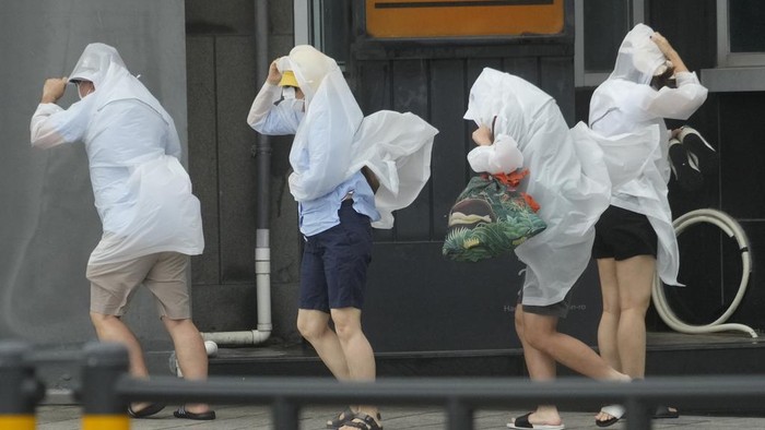 People struggle in the rain and wind as the tropical storm named Khanun approaches to the Korean Peninsular, in Busan, Thursday, Aug. 10, 2023. (AP Photo/Ahn Young-joon)
