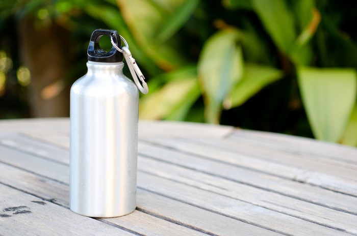 Reusable water bottle on a wooden table outdoors