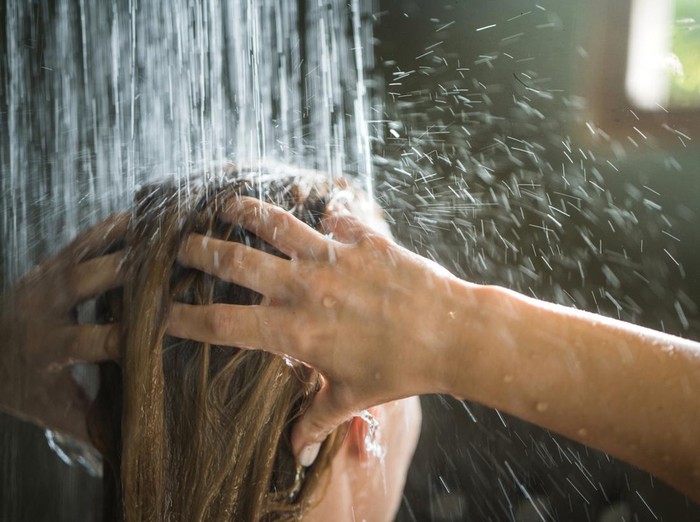 Close up of a woman washing her hair while showering in the morning.