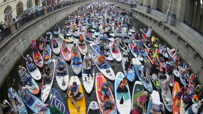 People steer their stand-up paddle (SUP) boards along the Griboedov Channel during the annual costumed 'Fontanka' SUP-boards festival in St. Petersburg, Russia, Saturday, Aug. 5, 2023. (AP Photo/Dmitri Lovetsky)