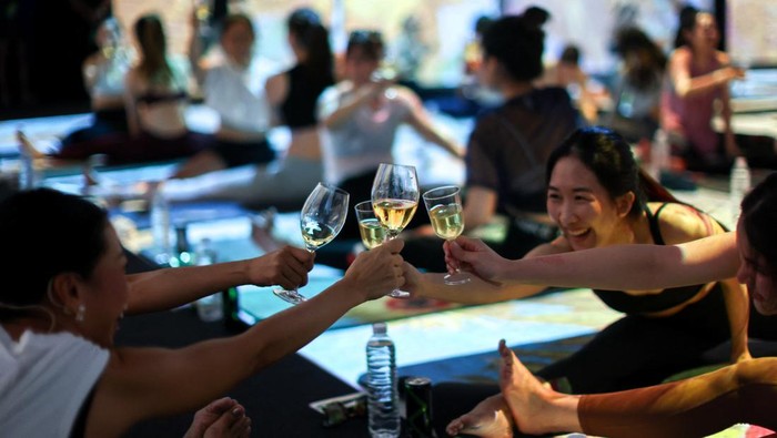 Yoga enthusiasts perform a yoga exercise in a wine yoga class inside 