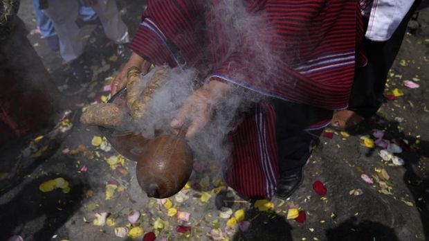 A shaman holds sweet potatoes and an instrument during a shamanic ritual calling for the earth's protection from contamination, one day before Earth World Day on San Cristobal hill in Lima, Peru, Friday, April 21, 2023. (AP Photo/MartÌn MejÌa)