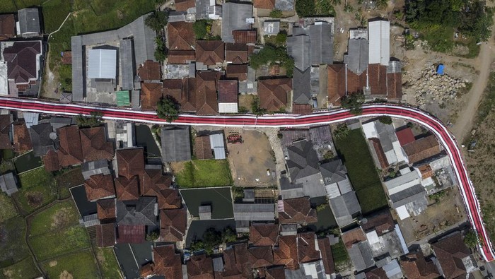 Foto udara lorong bendera Merah Putih bertema Terus Melaju untuk Indonesia Maju yang terbentang di Desa Sukamenak, Kabupaten Tasikmalaya, Jawa Barat, Sabtu (12/8/2023). Lorong bendera Merah Putih yang menghiasi jalan perkampungan sepanjang 250 meter itu dibuat warga secara swadaya dalam rangka memeriahkan HUT ke-78 Kemerdekaan RI. ANTARA FOTO/Adeng Bustomi/tom.