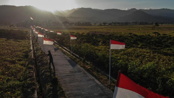 Warga melintas di dekat Bendera Merah Putih di Dusun Pejaten, Jatisarono, Nanggulan, Kulonprogo, DI Yogyakarta, Jumat (11/8/2023). Pemasangan 78 Bendera Merah Putih dan satu bendera raksasa berukuran 7,8 meter tersebut untuk menyambut HUT ke-78 Kemerdekaan RI. ANTARA FOTO/Hendra Nurdiyansyah/rwa.