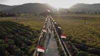 Warga melintas di dekat Bendera Merah Putih di Dusun Pejaten, Jatisarono, Nanggulan, Kulonprogo, DI Yogyakarta, Jumat (11/8/2023).