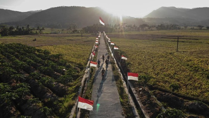 Warga melintas di dekat Bendera Merah Putih di Dusun Pejaten, Jatisarono, Nanggulan, Kulonprogo, DI Yogyakarta, Jumat (11/8/2023). Pemasangan 78 Bendera Merah Putih dan satu bendera raksasa berukuran 7,8 meter tersebut untuk menyambut HUT ke-78 Kemerdekaan RI. ANTARA FOTO/Hendra Nurdiyansyah/rwa.