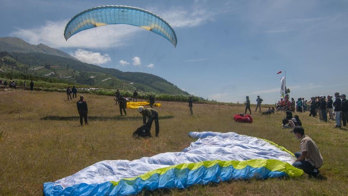 Wisata paralayang di lereng Gunung Merbabu Petugas membantu wisatawan merapikan parasut paralayang usai mendarat di lereng Gunung Merbabu, Tarubatang, Selo, Boyolali, Jawa Tengah, Sabtu (12/8/2023). Pemerintah setempat dan Kelompok Sadar Wisata (Pokdarwis) Tarubatang mengembangkan desa wisata dirgantara paralayang dan pengunjung dapat menikmati pemandangan Gunung Merbabu serta Gunung Merapi dengan tandem terbang paralayang berbiaya Rp300 ribu per orang. ANTARA FOTO/Aloysius Jarot Nugroho/tom.