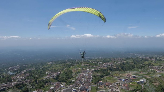 Petugas membantu wisatawan merapikan parasut paralayang usai mendarat di lereng Gunung Merbabu, Tarubatang, Selo, Boyolali, Jawa Tengah, Sabtu (12/8/2023). Pemerintah setempat dan Kelompok Sadar Wisata (Pokdarwis) Tarubatang mengembangkan desa wisata dirgantara paralayang dan pengunjung dapat menikmati pemandangan Gunung Merbabu serta Gunung Merapi dengan tandem terbang paralayang berbiaya Rp300 ribu per orang. ANTARA FOTO/Aloysius Jarot Nugroho/tom.