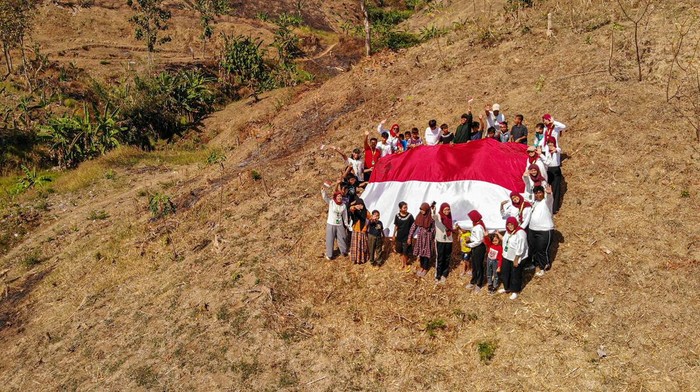 Sejumlah anak membentangkan bendera Merah Putih di Desa Pinggir, Lengkong, Nganjuk, jawa Timur, Minggu (13/8/2023). Aksi membentangkan bendera Merah Putih di salah satu daerah pelosok di Nganjuk tersebut merupakan bentuk upaya pemuda setempat untuk menanamkan semangat kemerdekaan kepada masyarakat khususnya anak-anak di desa itu.