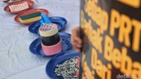 Di bawah tenda di mana mereka duduk sambil melakukan aksi mogok makan, terlihat sejumlah piring berisikan alat-alat rumah tangga seperti sponge cuci piring, dot bayi, sikat, hingga rantai.  