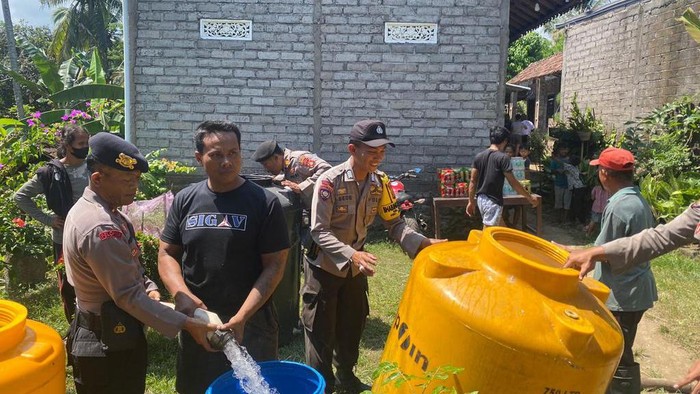 Anggota kepolisian Polres Jembrana saat mendistribusikan air bersih di Lingkungan Pancardawa, Kelurahan Pendem, Kecamatan Jembrana, Kabupaten Jembrana, Bali, Senin (14/8/2023).